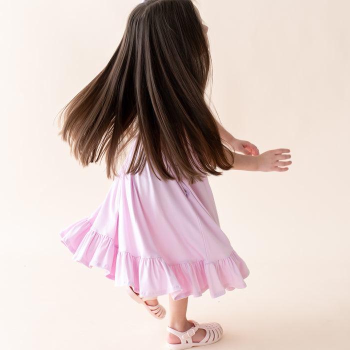 Child in a purple dress twirling on a plain background