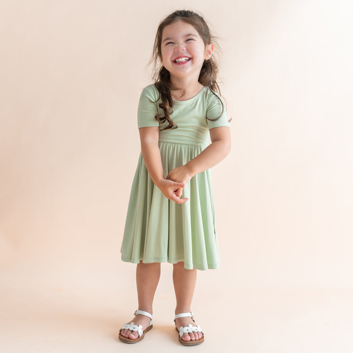 Young girl wearing a light green dress against a beige background