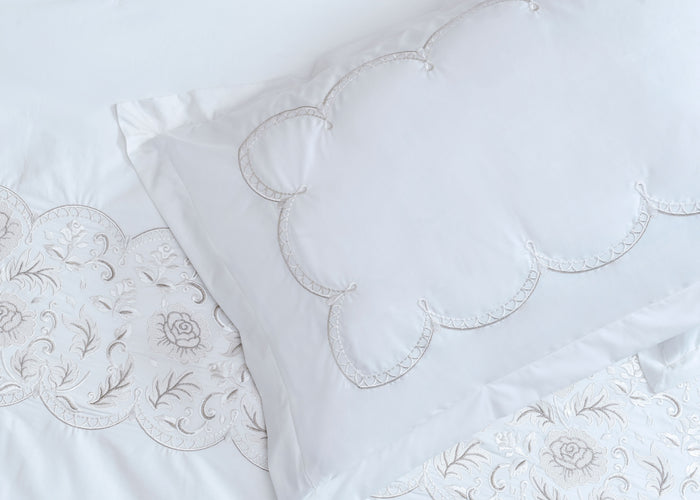 White pillow sham and duvet panels with embroidered floral sprigs and decorative stitching