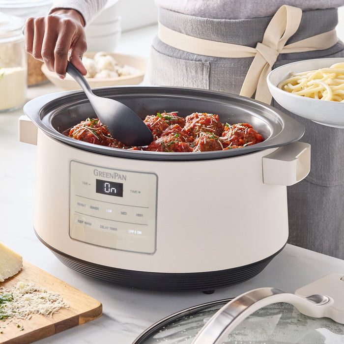 Serving meatballs from an 8-quart slow cooker with locking lid, next to pasta and cheese on a kitchen counter.