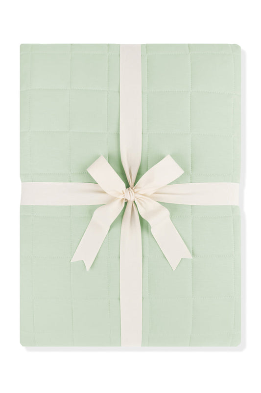Adult Quilted Blanket in Basil 1.0 shown in its packaging tied with a linen bow