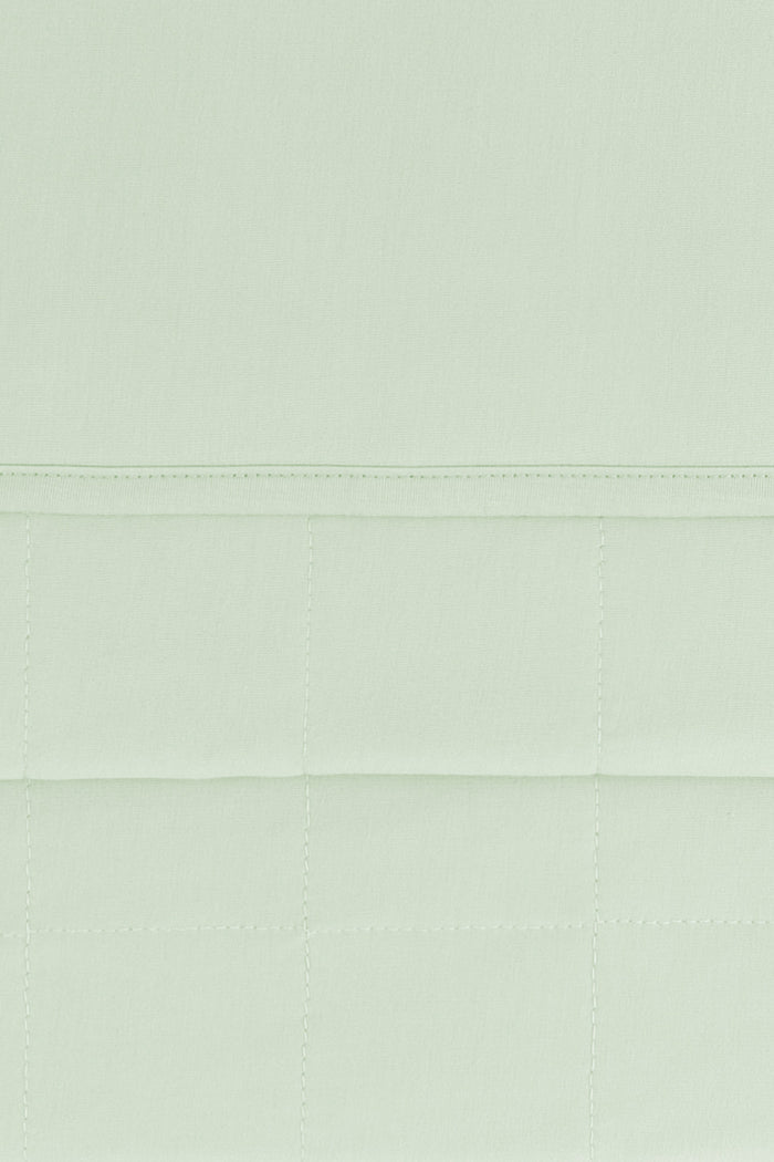 Close up of the quilted bottom and smooth top layer of the Adult Quilted Blanket in Basil 1.0