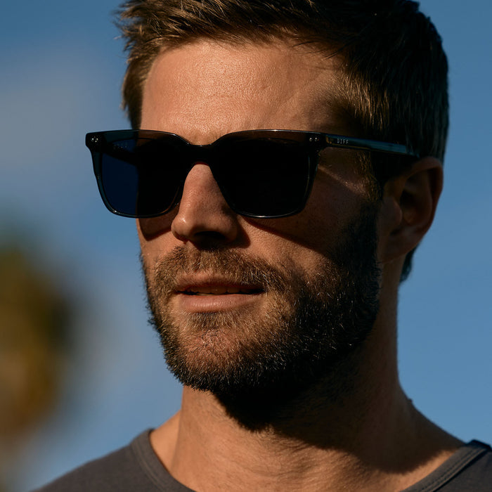 lifestyle - male wearing (davey fisher) wearing diff eyewear featuring the billie xl square sunglasses with a black smoke crystal frame and grey polarized lenses detailed view