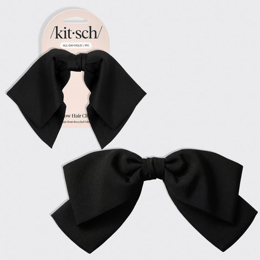 A black bow hair clip shown both on its retail backing card and as a loose product shot, on a light gray background. The brand name 'kitsch' is visible on the card.
