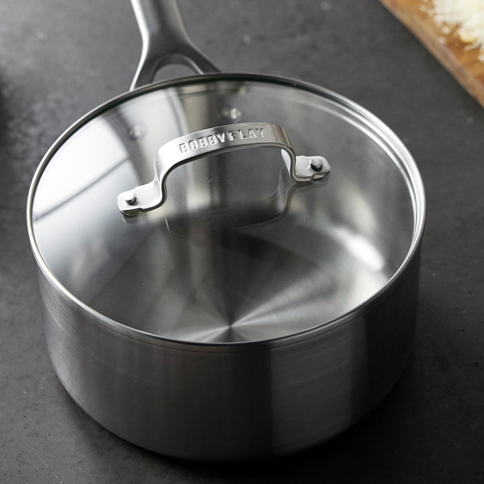 Stainless steel saucepan with glass lid on a dark counter, holds 3 quarts, single piece.