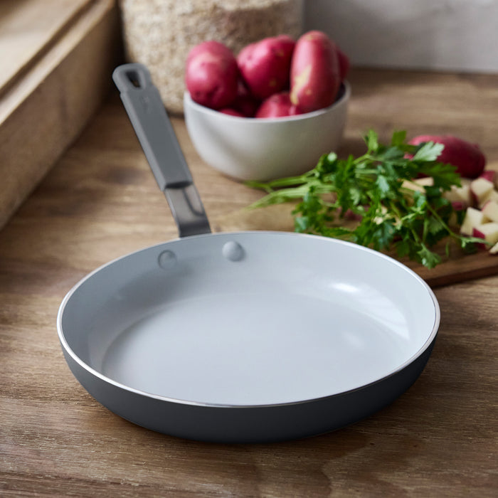 Graphite ceramic nonstick frypan by Bobby Flay sits beside red potatoes and parsley on a countertop.