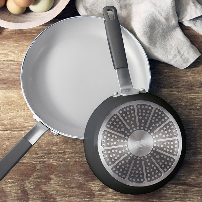 Set of two graphite ceramic nonstick frypans showing interior and base on a wooden surface.