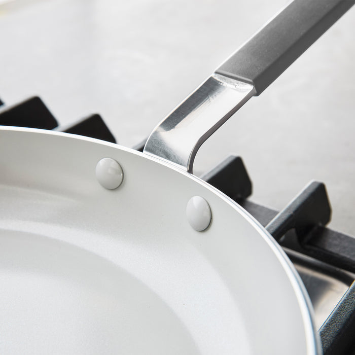 Gray ceramic nonstick frypan with metal handle on a stovetop, 10-inch size, single piece shown.