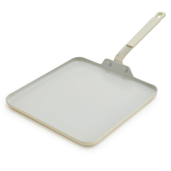 Cream ceramic square griddle pan with long handle on white background.