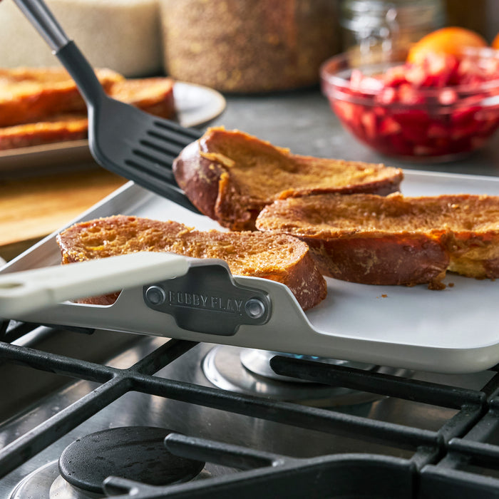 French toast cooking on a GreenPan 11-inch ceramic nonstick square griddle with strawberries nearby.