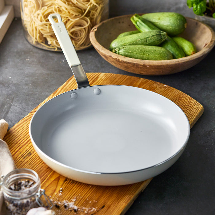 Cream-colored ceramic nonstick 12-inch frypan on a kitchen counter.