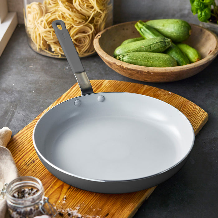 GreenPan ceramic nonstick frypan on a board with zucchini and pasta jars in the background.