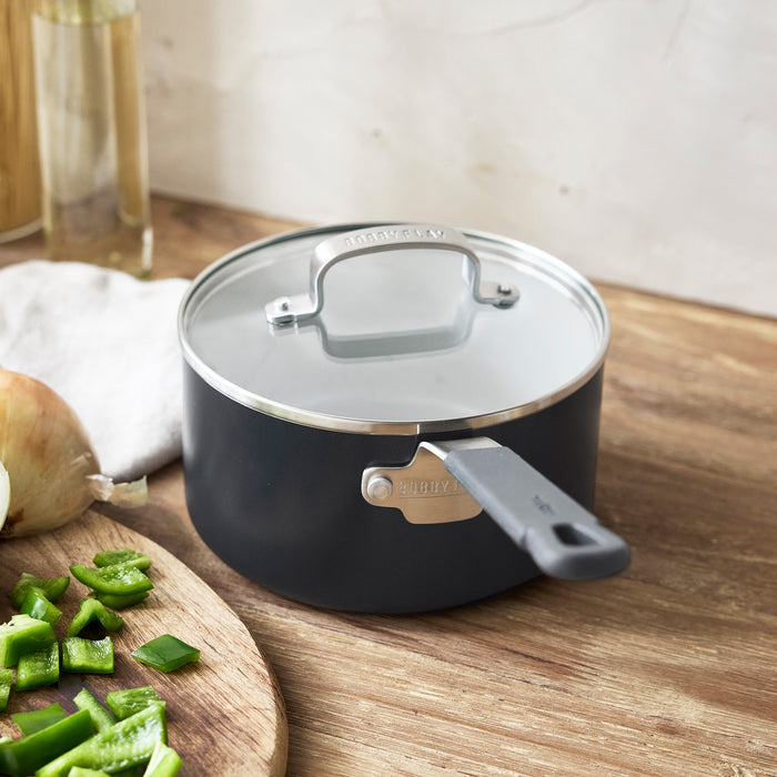 GreenPan 1.6-qt saucepan with lid next to a cutting board holding chopped peppers and onion.