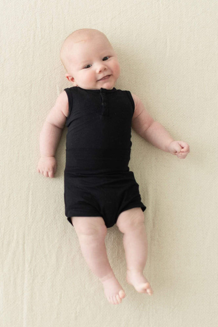 Smiling infant wearing Kyte Baby Bummies in Midnight and matching bodysuit