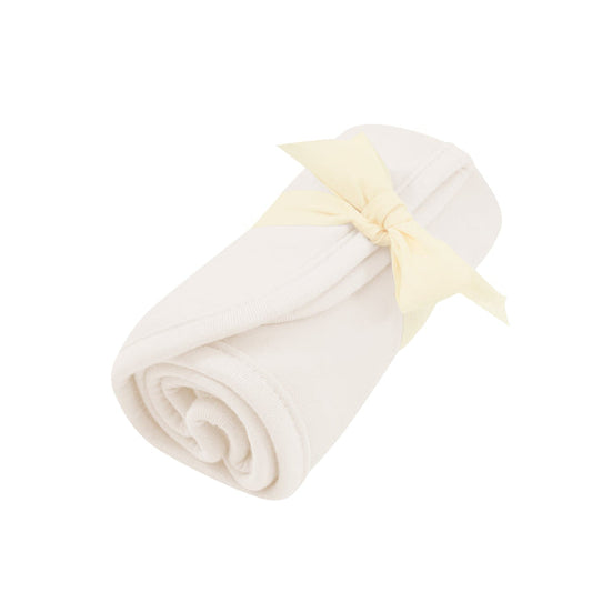 Rolled up Burp Cloth in Oat with bow tied around it
