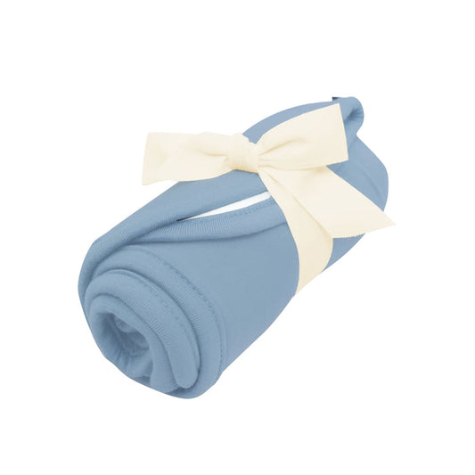 Rolled up Kyte Baby Burp Cloth in Slate with bow tied around it