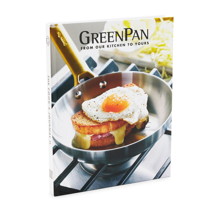 Cook's Journal Cookbook, Vol. 2 features a cover with a fried egg on melted cheese and bread in a stainless steel pan on a stovetop, packed with delicious PFAS-free GreenPan recipes.