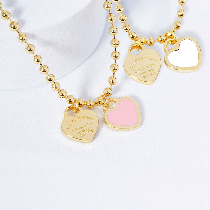 Gold beaded necklace with heart-shaped charms on a white background