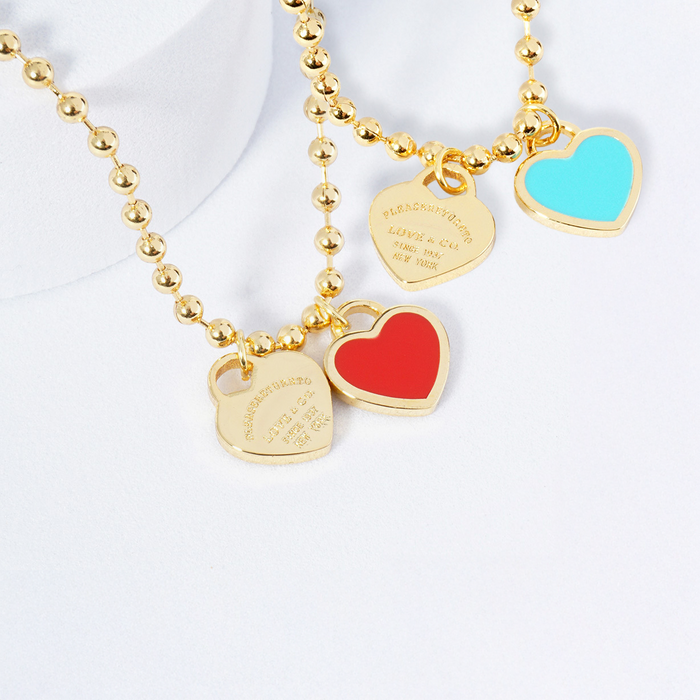 Gold beaded necklace with colorful heart charms on a white background
