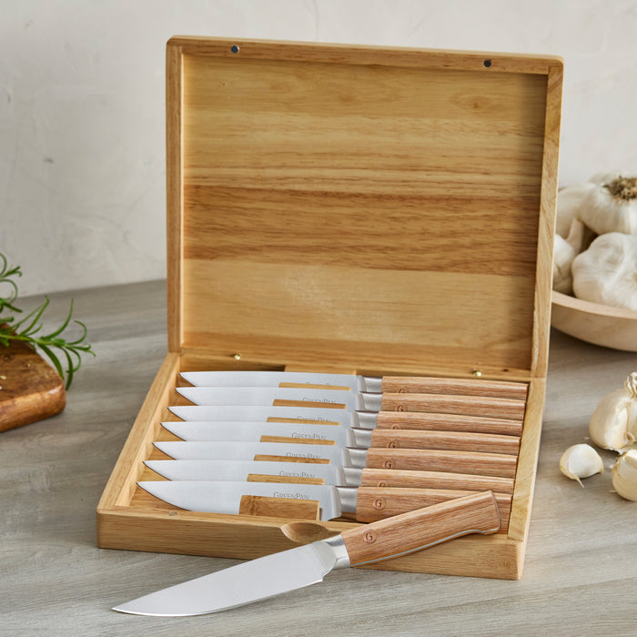 Set of knives in a wooden box on a countertop with garlic in the background