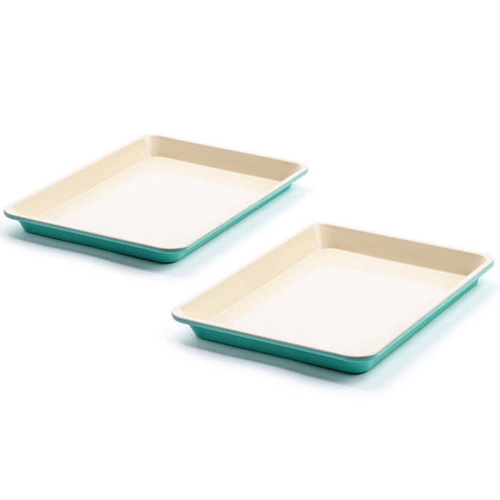 Set of two ceramic cookie sheets with cream interiors and teal exteriors on a white surface.