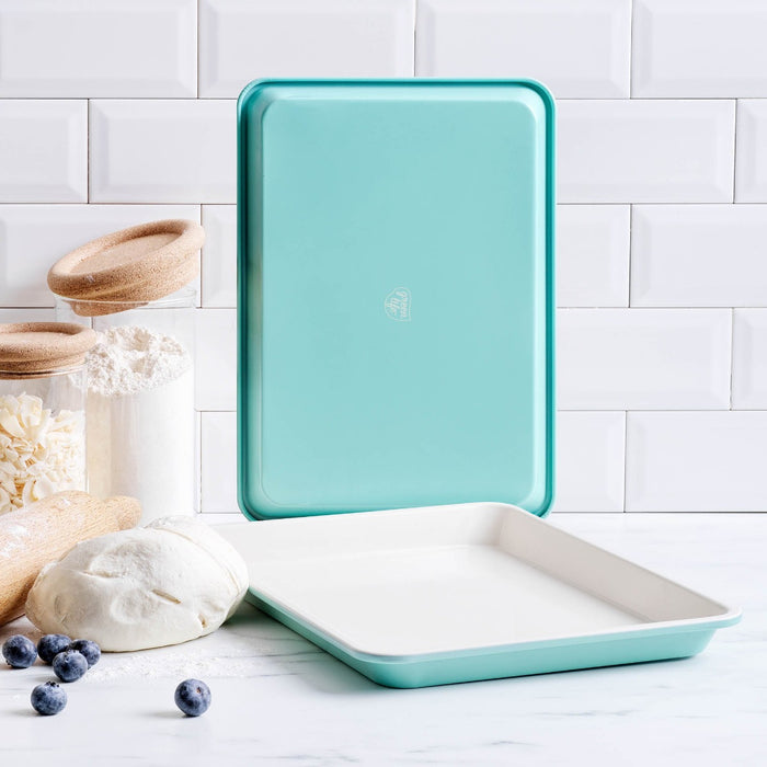 GreenLife ceramic nonstick cookie sheet set, 13 x 9, with baking ingredients and blueberries on a white countertop.