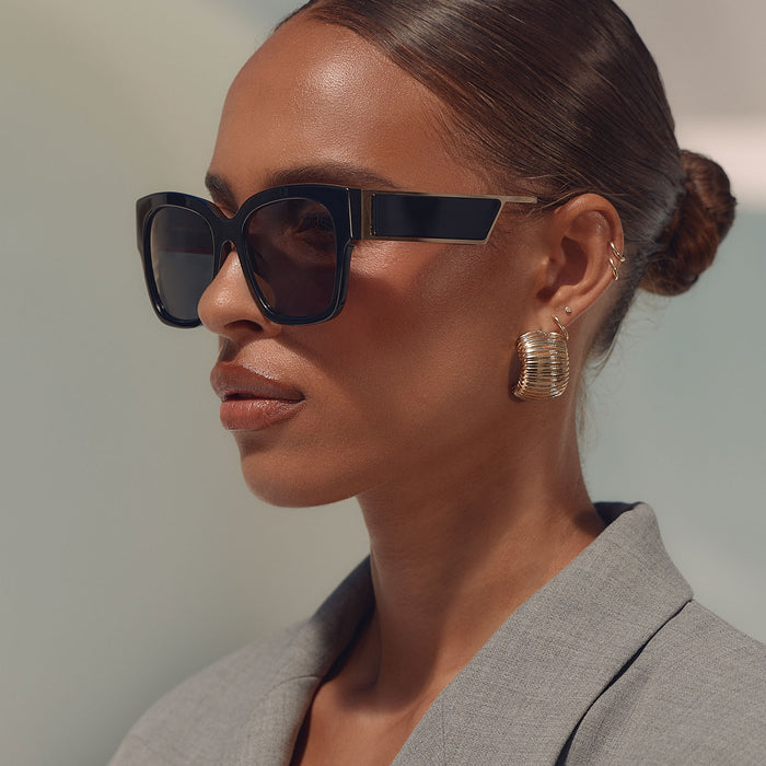 on model - female business woman wearing diff eyewear isabella square sunglasses with a black frame and grey polarized lenses angled view