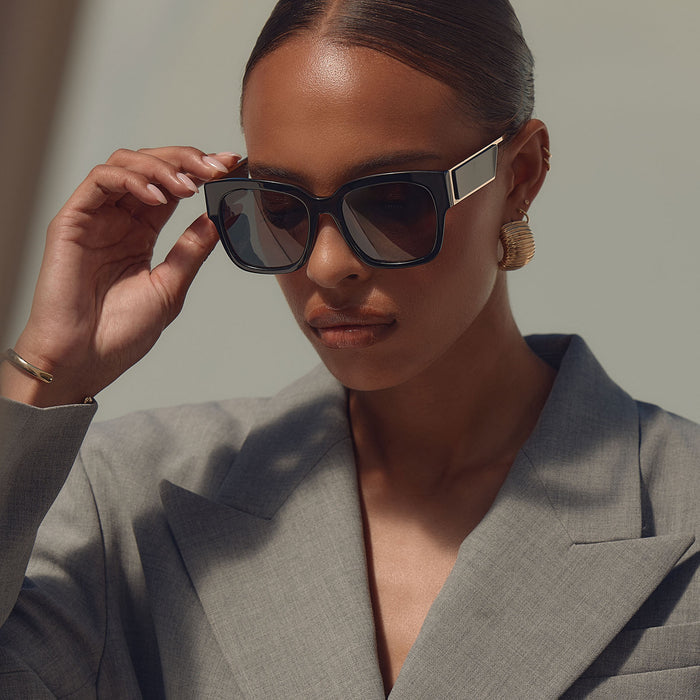 on model - female business woman taking off diff eyewear isabella square sunglasses with a black frame and grey polarized lenses