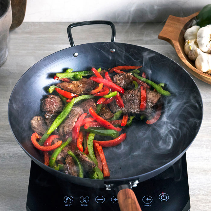 Black wok with beef and vegetables on an induction cooktop