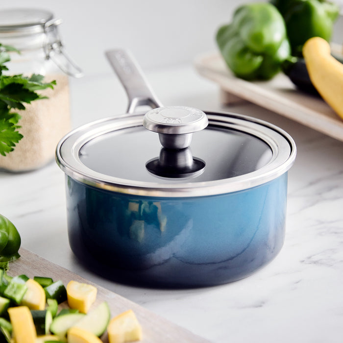 Aegean teal enameled steel 1.5-quart saucepan with lid on a marble countertop.