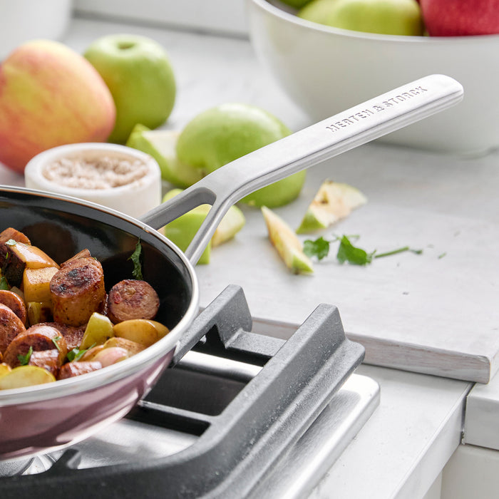 The Merten  Storck Steel Core Enameled 9.5 Frypan | Chocolate Truffle cooks sausage, veggies, and apples on the stove.