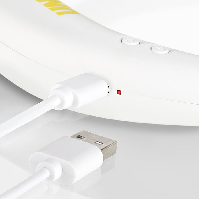 Nahaufnahme eines weißen USB-Kabels, das an den Unold NACKENVENTILATOR BREEZY angeschlossen ist. Die rote Kontrollleuchte und die Steuertasten sind zu sehen. Ein weiteres nicht angeschlossenes USB-Kabel liegt in der Nähe auf einer weißen Oberfläche.