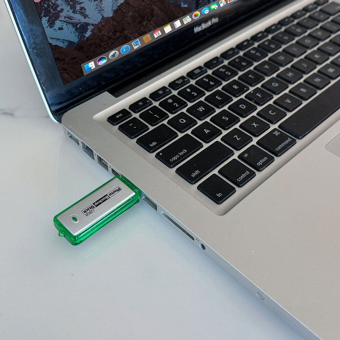 Green USB drive inserted into a laptop on a light surface