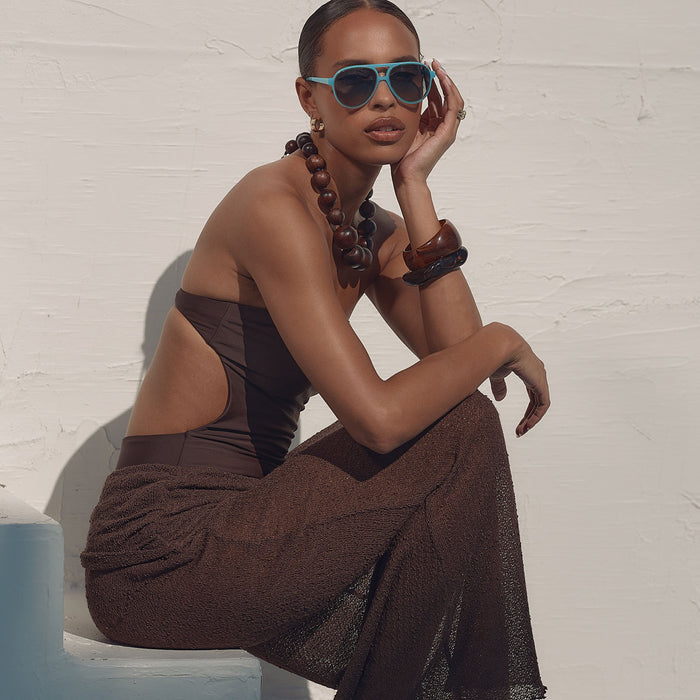 lifestyle - female sitting on a step wearing iconica x diff eyewear pia oversized aviator sunglasses with a parasido blue acetate frame and paradiso blue polarized lenses front view
