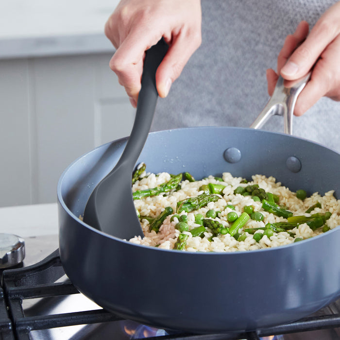 Gray silicone spatula from 4-piece set stirring rice and asparagus in a pan.