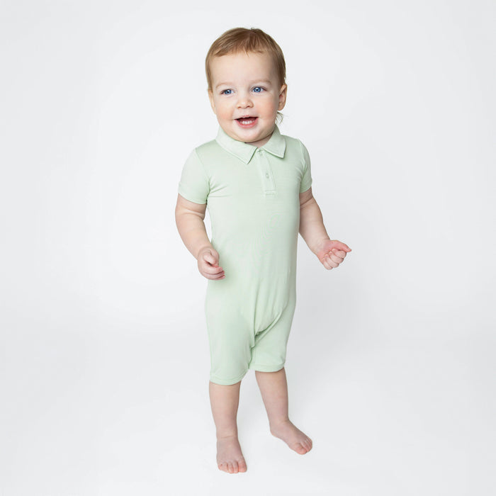 Young toddler wearing the Polo Shortall in Basil standing in front of a white background
