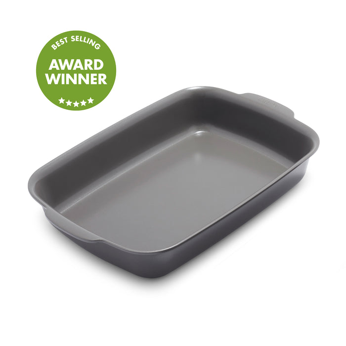 Gray ceramic rectangular baker with handles, shown beside a green circular award badge.