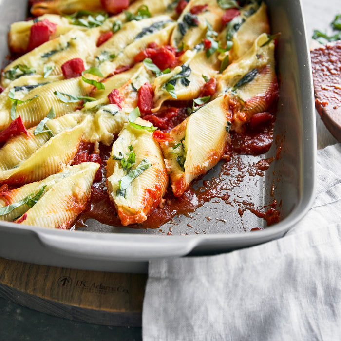 Gray ceramic 13x9 baker filled with stuffed pasta shells, tomato sauce, and melted cheese.