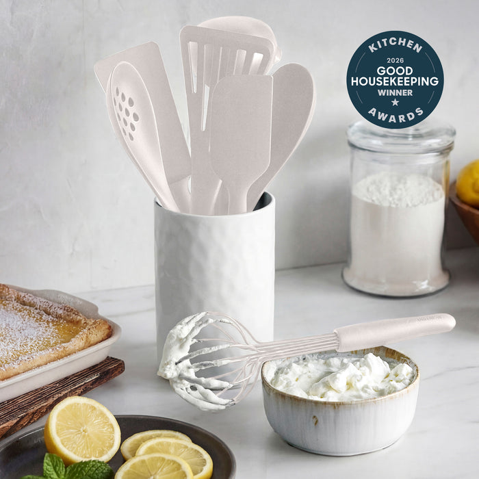 8-piece silicone utensil set with crock in bisque, displayed with whipped cream, lemons, and an award badge.