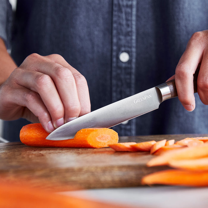 Slicing a carrot with a 5 walnut-handled utility knife on a wooden cutting board.