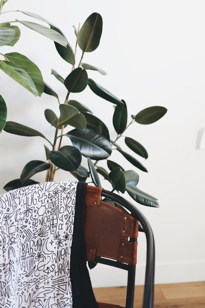 Artistic shot of the quilt draped over a chair with houseplants behind.