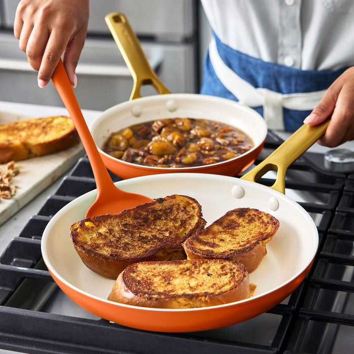Person cooking French toast in a dark orange frypan on a stove
