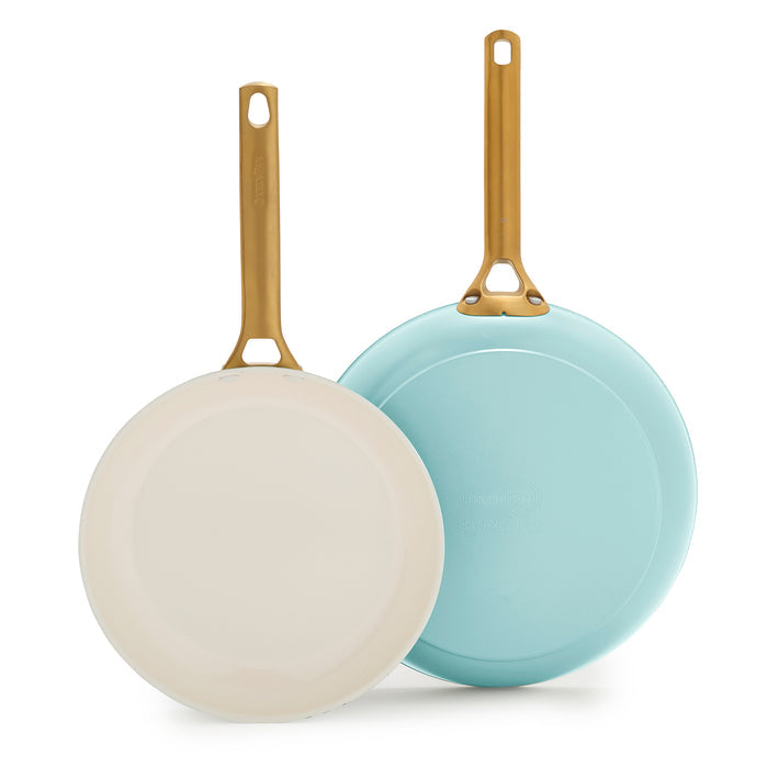 Two light blue frying pans with gold handles on a white background