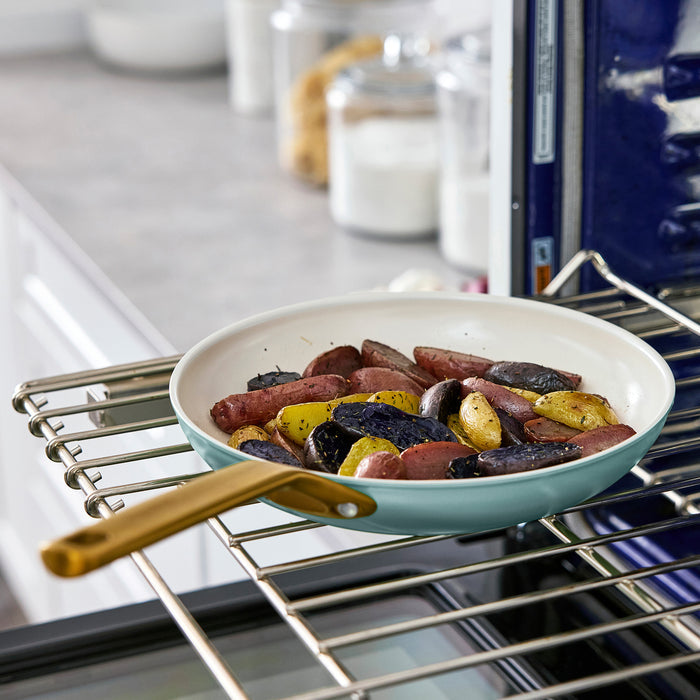 Light blue frying pan with sausage and potatoes in an oven