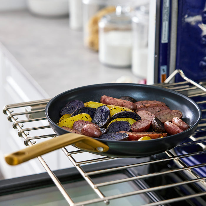 Black frying pan with sausages and potatoes in an oven