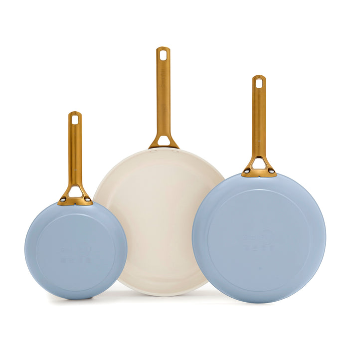 Three blue frying pans with gold handles on a white background