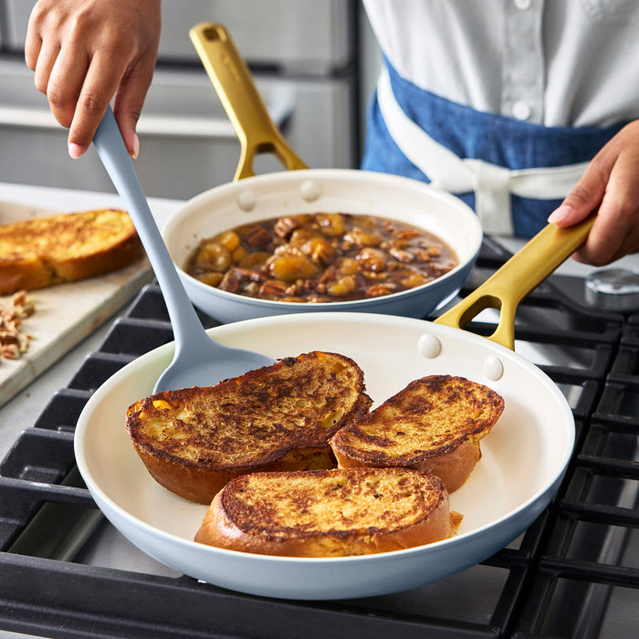 Person cooking French toast in a light blue frying pan on a stove