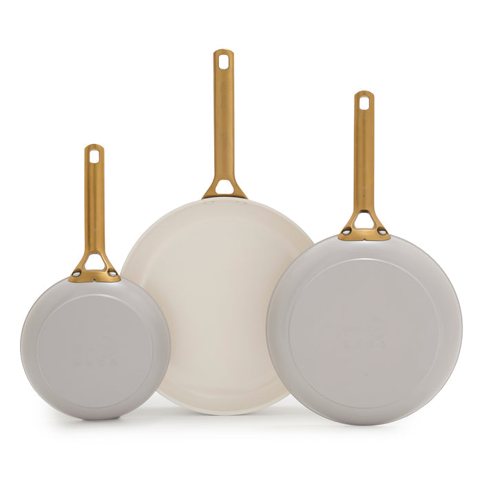 Three taupe gray frying pans with gold handles on a white background
