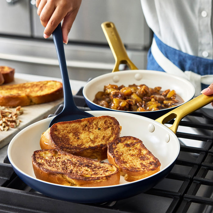 Person cooking French toast in dark blue frypans with a spatula