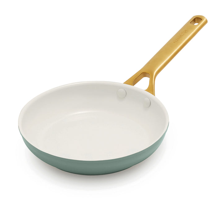 Green frying pan with a gold handle on a white background